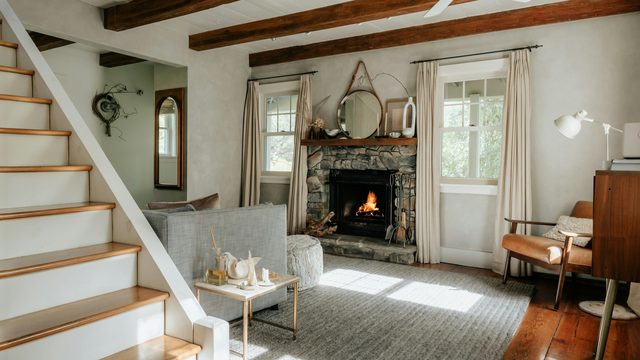 A cozy living room with a stone fireplace and natural light
